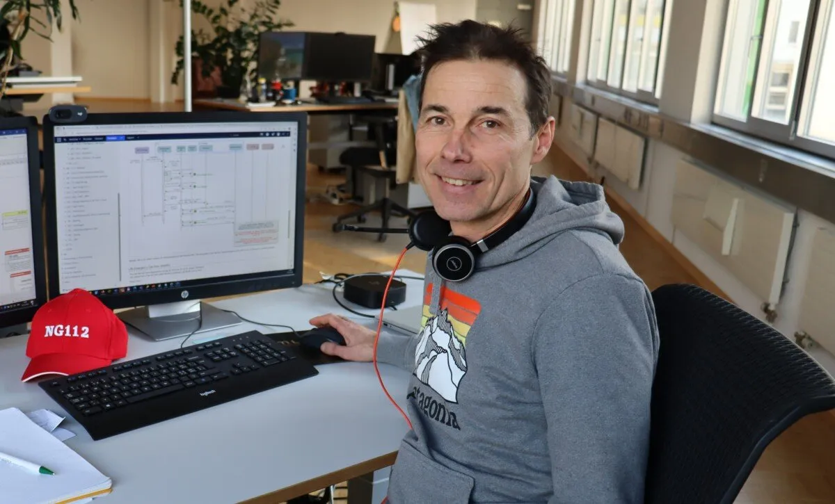Hans-Peter Schmocker an seinem Arbeitsplatz bei Intersys, daneben eine rote NG112-Mütze